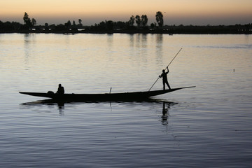 A boat and its crew are silhouetted against the River Bani at dusk in Mopti, Mali on 8 December 2007