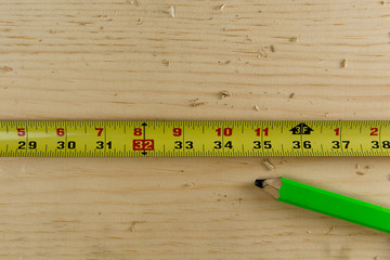 top view of tape measure and pencil on a wooden board