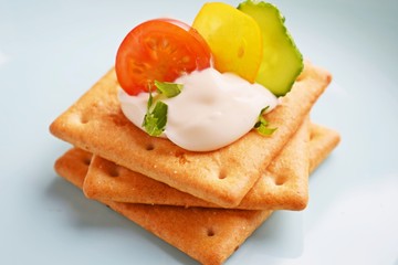Delicious crackers with cheese sauce and vegetables.Snack on wooden background.