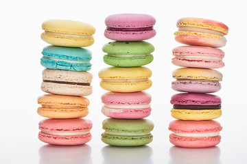 three rows of sweet multicolored French macaroons of different flavors on white background