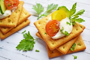 Fototapeta na wymiar Delicious crackers with cheese sauce and vegetables.Snack on wooden background.