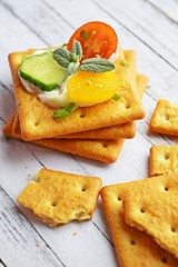 Delicious crackers with cheese sauce and vegetables.Snack on wooden background.