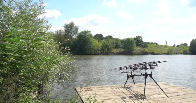 Slow motion, carp fishing, rod under, fishing rods, reels on a wooden platform