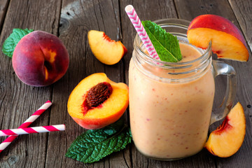 Healthy  peach smoothie in a mason jar glass. Close up table scene against a rustic wood background.