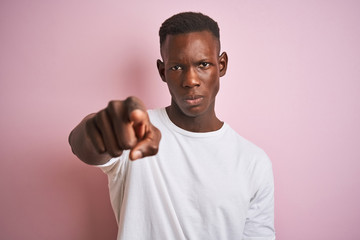 African american man wearing white t-shirt standing over isolated pink background pointing with finger to the camera and to you, hand sign, positive and confident gesture from the front