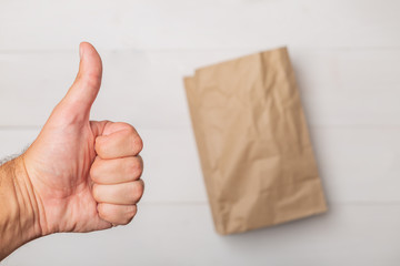 Grocery shopping paper bag and male hand giving thumb up