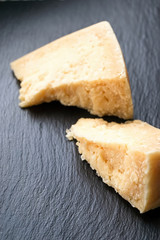 Parmesan cheese on black stone background. Top view, copy space.
