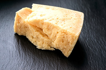 Parmesan cheese on black stone background. Top view, copy space.