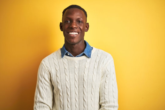 African american man wearing denim shirt and white sweater over isolated yellow background with hands together and crossed fingers smiling relaxed and cheerful. Success and optimistic