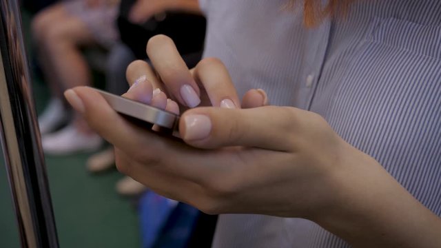 Close-Up Of Woman Hands Using Smartphone Standing In Subway Car