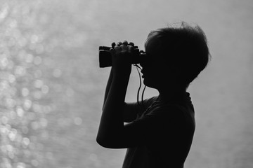 Black and white photography of cute happy kid wathing in old vintage binocular at something...