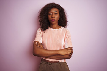 Obraz premium Young african american woman wearing t-shirt standing over isolated pink background skeptic and nervous, disapproving expression on face with crossed arms. Negative person.