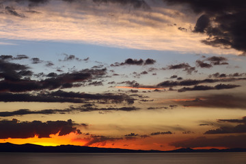 Colorfully lit evening sky with dark clouds shortly after sunset over Lake Titicaca viewed from the small tourist town of Copacabana in Bolivia