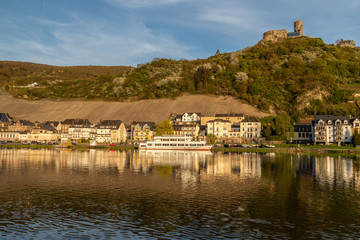 Fototapeta na wymiar View at the city of Bernkastel-Kues at river Moselle with passenger ships and mountains with vineyards in the background