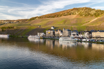Obraz premium View at the city of Bernkastel-Kues at river Moselle with passenger ships and mountains with vineyards in the background