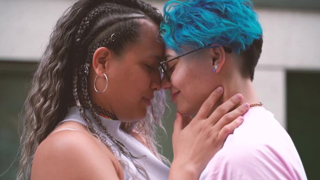 Sweet and tender kiss between two women in love. Public shown of affection. Free love to all sexual orientation. Teenager love.Gay young relationship. Blue short hair lesbian icon.