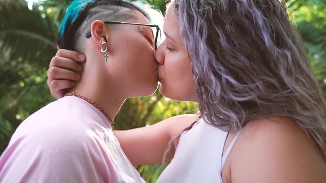 Sweet kiss on a tropical sunset. Young lesbian couple showing affection in public. Love without boundaries. Love is love. Proud to be gay. European pride forever.