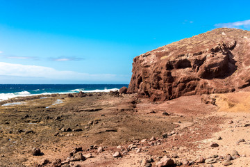 A view of red Mount Bocinegro and rocky coastline near El Medano town, Tenerife, Spain