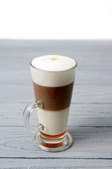 A glass of caffe macchiato with honey on the table