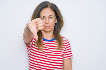 Middle age senior woman standing over white isolated background looking unhappy and angry showing rejection and negative with thumbs down gesture. Bad expression.