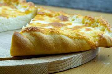 Freshly baked khachapuri with cheese on a wooden board.