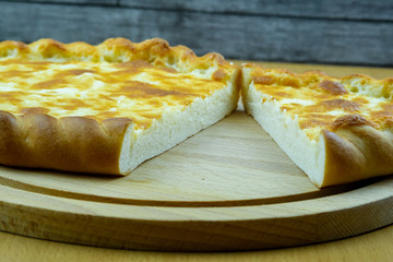 Freshly baked khachapuri with cheese on a wooden board.