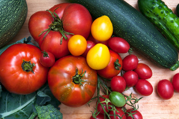  Fresh large and small tomatoes and vegetables on a flat lay table