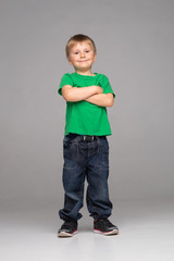 Portrait of happy smiling boy in green t-shirt and jeans. Attractive kid in studio.