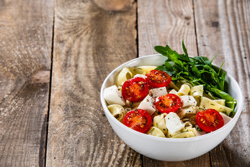Pasta with tomatoes and white cheese on wooden table