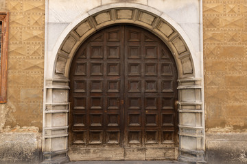 Fototapeta na wymiar antica porta in legno ad arco con decorazioni italia