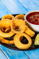 Onion rings with sauce on wooden table