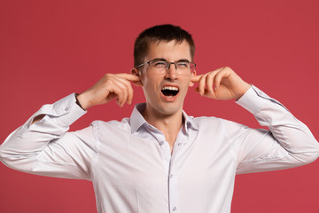 Young man in a classic white shirt is posing over a pink background.