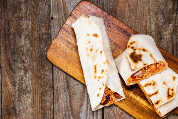 Burritos on cutting board on wooden table