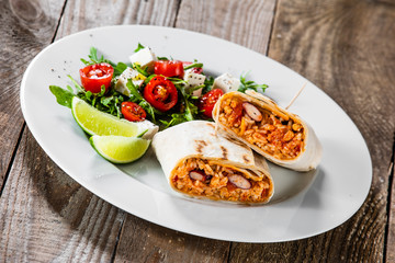 Burrito with vegetable salad on white plate