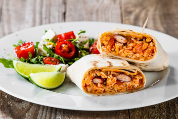 Burrito with vegetable salad on white plate