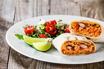 Burrito with vegetable salad on white plate