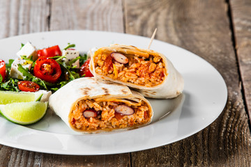 Burrito with vegetable salad on white plate