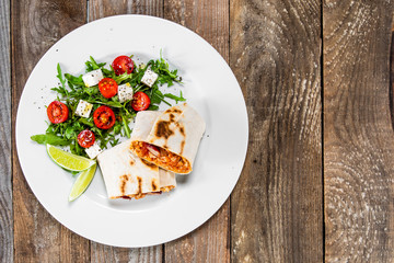 Burrito with vegetable salad on white plate