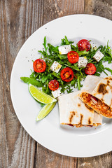 Burrito with vegetable salad on white plate