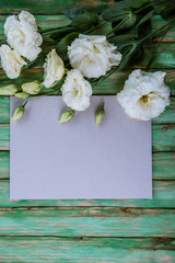 beautiful eustoma flowers with white frame on wooden background