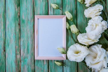 beautiful eustoma flowers with white frame on wooden background