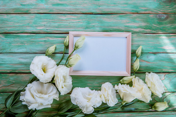 beautiful eustoma flowers with white frame on wooden background