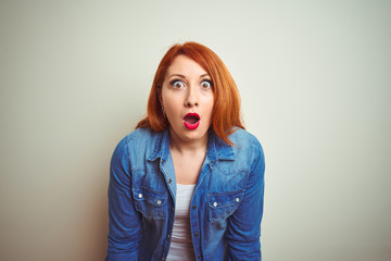 Young beautiful redhead woman wearing denim shirt standing over white isolated background afraid and shocked with surprise expression, fear and excited face.