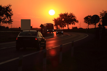 Samochody na drodze o zachodzie słońca. - obrazy, fototapety, plakaty