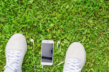 Sneakers on the green grass with a mobile phone and headphones