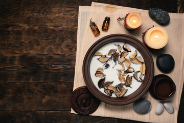 Aromatherapy concept background. Milk in a bowl with incense and essential oil on a brown wooden table background.