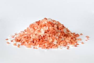 Fototapeta na wymiar Heap of pink himalayan salt crystals on white background. Himalayan salt is used in cooking, medicine and cosmetology.