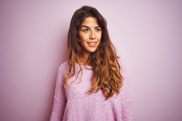 Fototapeta premium Young beautiful woman wearing sweater standing over pink isolated background looking away to side with smile on face, natural expression. Laughing confident.