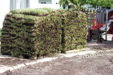 Sod on pallets delivered by tractor to residential address for placement