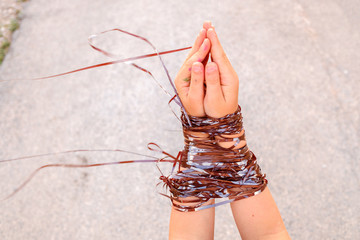 A child's hands tied with ribbon playing to be caught.